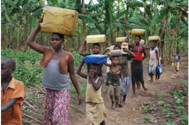 A woman and some children in the area carrying water from a stream