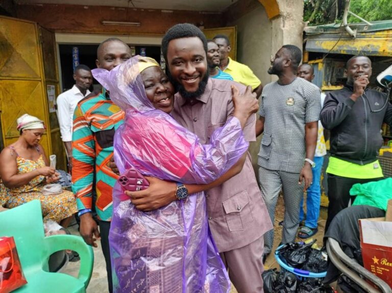 Dennis Obeng Agyei, Assembly Member of Oda Nkwanta Electoral Area, hugs a beneficiary of the raincoat donation